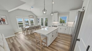 A spacious kitchen with a large island, white cabinetry, and a dining area with a view.