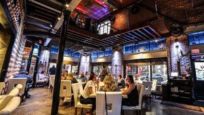 An indoor dining area with brick walls, exposed ceilings, and a mix of natural and artificial lighting. - Luxury in the sky (Fort Myers)