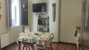 A small dining area with a table and chairs, a television mounted on the wall, and a bookshelf with books. - Acomodis great location right in El Born old town 4 air conditioners 6 ppl max.! (Barcelona)