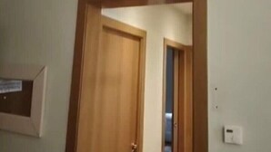 Ein Zimmer mit Holztür, einer weißen Wandklimaanlage und einem Lichtschalter an der Wand.