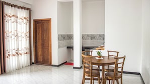 Un coin repas avec une table et des chaises en bois, une plante en pot et une vue sur un mur carrelé orné d’un motif d’arbre.