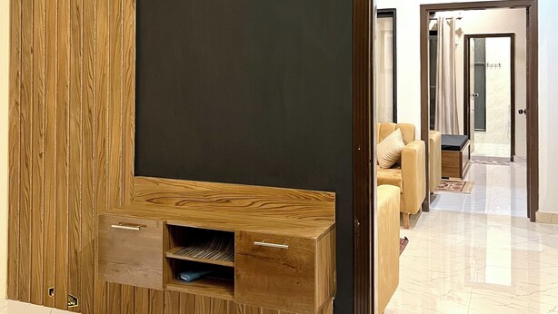 A modern interior with a wooden accent wall, a dark partition, and a reflective floor. - Entire 2 Bedroom Suite 5 (Islamabad)