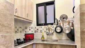 A kitchen with wooden cabinets, a red stove, a sink, and various kitchen utensils. - Entire 2 Bedroom Suite 5 (Islamabad)