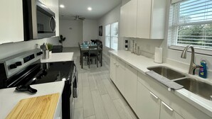 Una cocina moderna con armarios blancos, una estufa negra y una zona de comedor con mesa y sillas.