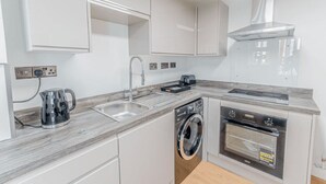 A modern kitchen with a built-in dishwasher, oven, and sink. - Chic city flat with parking, near the waterfront (Stonehouse)