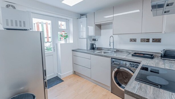 A modern kitchen with white cabinets, a built-in dishwasher, a sink, and a stove. - Chic city flat with parking, near the waterfront (Stonehouse)