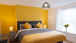 A modern bedroom with a bed, bedside tables, a window with a view, and a hanging light fixture. - Chic city flat with parking, near the waterfront (Stonehouse)