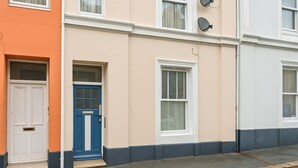 Une rangée de maisons mitoyennes, chacune ayant une porte d’entrée distincte, l’une bleue et l’autre blanche, et une façade beige.