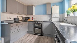 Une cuisine moderne avec des meubles de couleur grise, un four encastré, un four à micro-ondes et un évier.