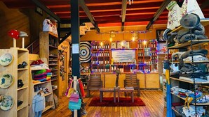 Een gezellige, goed verlichte winkel met houten vloeren en planken vol met diverse artikelen, zoals hoeden, flessen en opgevouwen kleding.