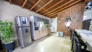 A kitchen with a stainless steel refrigerator, wooden cabinets, a microwave, and a sink. - 6 Bedroom Penthouse with Arcade Machine (Medellín)
