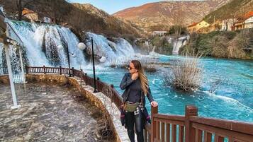 Un sendero de piedra que conduce a una baranda de madera con vistas a un río y una cascada.