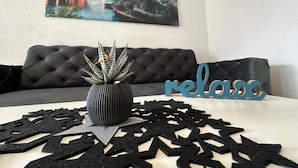 A living room with a black sofa, a decorative vase, and a wall-mounted painting.