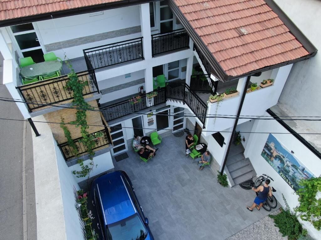 Um edifício residencial com vários andares, um pátio interno, varandas com plantas e uma bicicleta estacionada na frente.