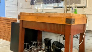 A bar area with a television displaying a movie poster, a fan, and various bar tools.