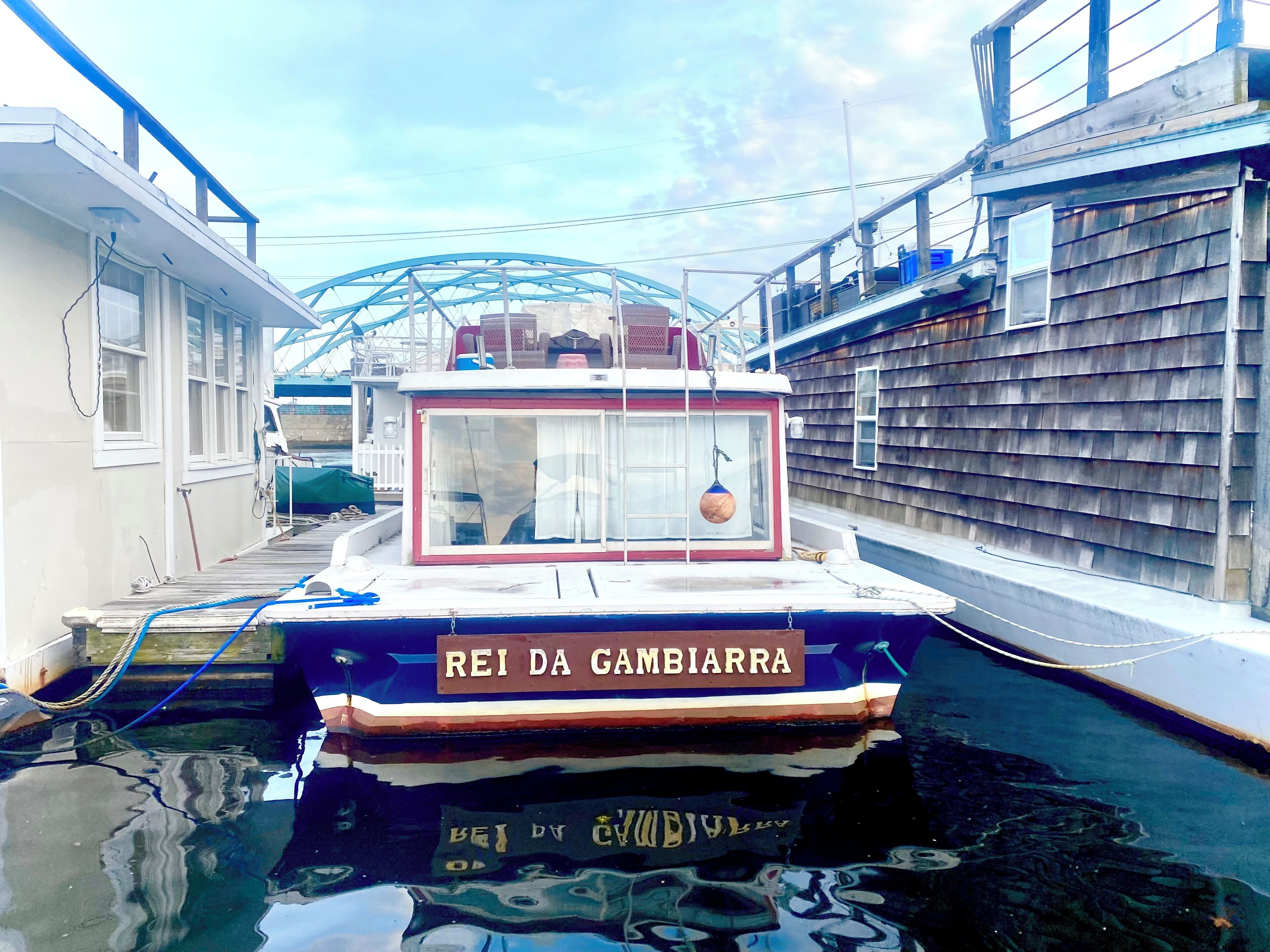 A narrow canal with a boat named "REI DA GAMBIARRA" docked at a pier.