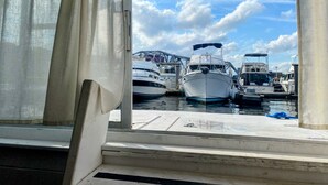 A marina with several boats docked, a clear sky, and a view through a window with curtains.