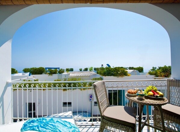 A balcony with a view of buildings, a table with fruits and a basket, and a chair. - La Coccinella House Praiano (Praiano)