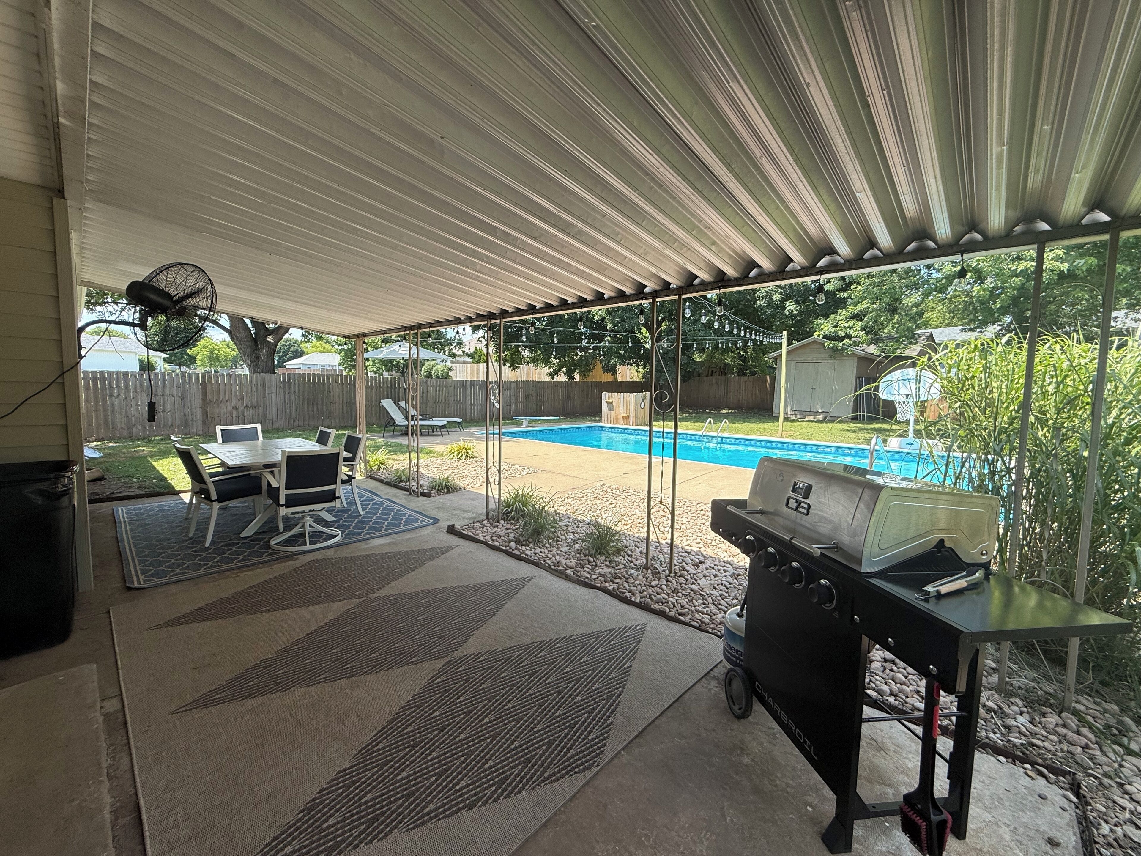 Una veranda coperta con barbecue, tavolo da pranzo e sedie.