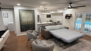 Ein modernes Schlafzimmer mit einem Bett, zwei Stühlen, einem Schreibtisch und einem großen Gemälde.