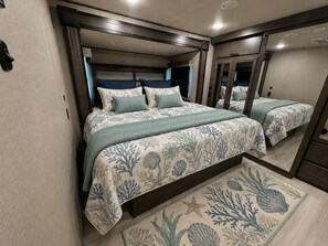 Un dormitorio con dos camas, un ventanal grande y un cabecero de madera.