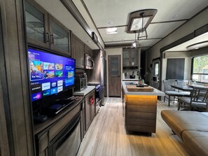 Un interior de autocaravana moderno con cocina, comedor y área de entretenimiento.