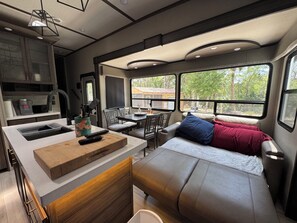 Interior compacto de una autocaravana con kitchenette, comedor y litera.