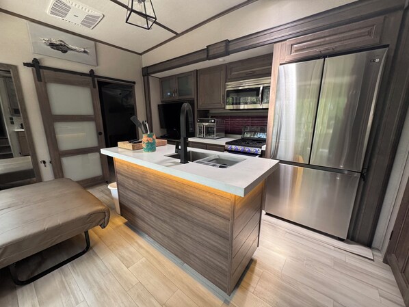 Una cocina moderna con una isla central, electrodomésticos de acero inoxidable y un armario de madera.