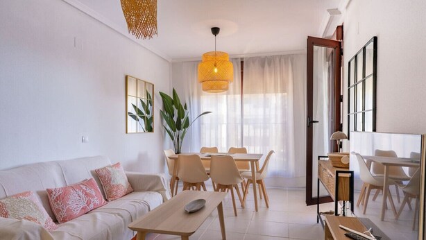 Una sala moderna con un sofá, una mesa de comedor, sillas y un televisor.