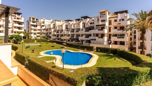 Un edificio residencial con varios balcones, piscina y jardines bien cuidados.