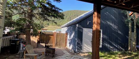 A stone patio with wooden furniture, a wooden pergola, and a garage.