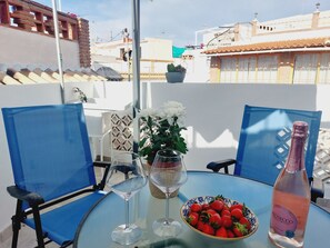 A table with a bottle of Prosecco, a bowl of strawberries, a glass of water, and a vase with white flowers. - Andalusian House with Sea View in the Old Town (Almuñécar)