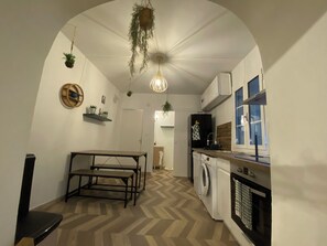 Cocina compacta con piso de espiga, una mesa de comedor, lavadora y una lámpara colgante.