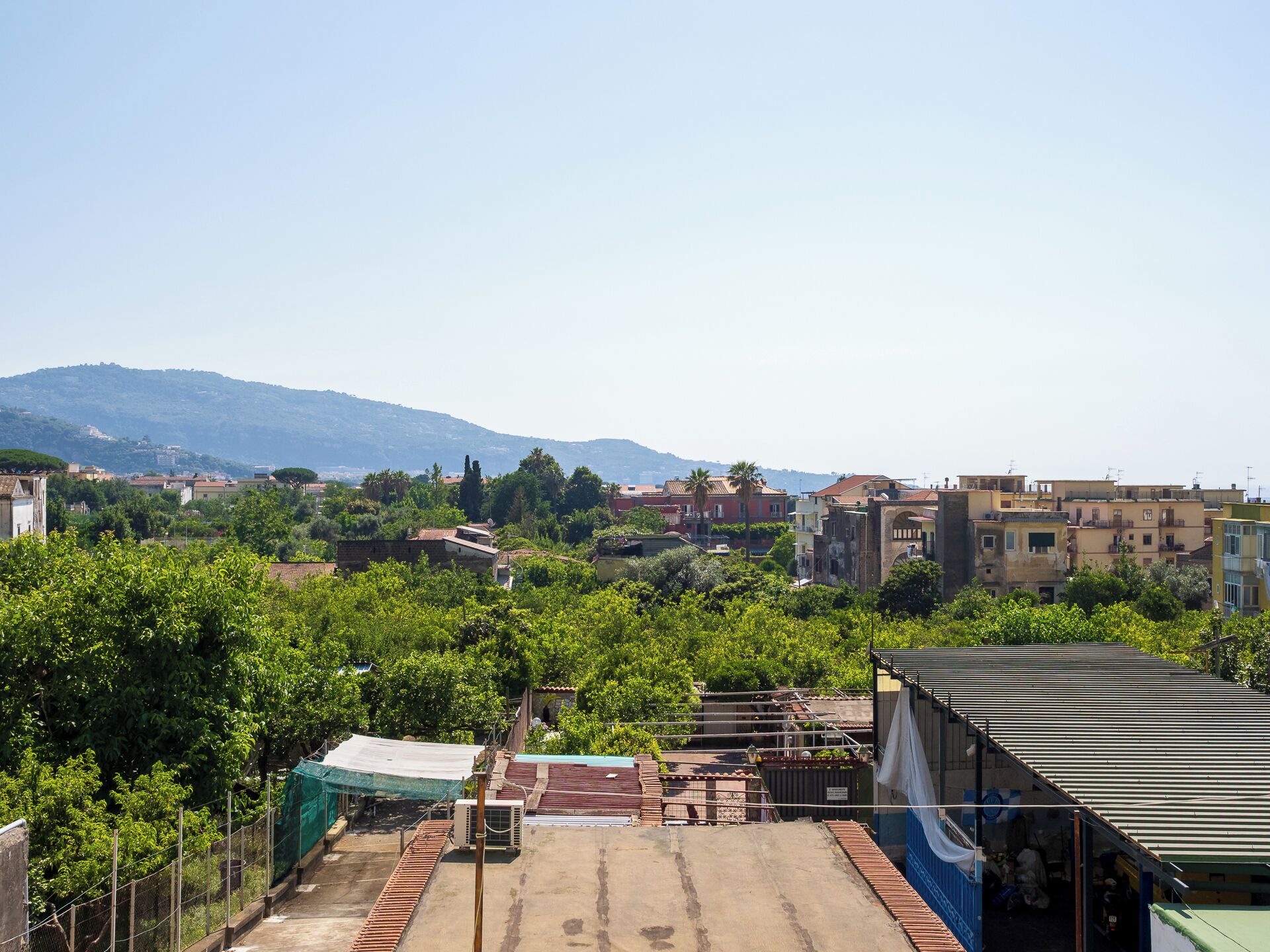 A rooftop with a view of a cityscape, including buildings and a distant mountain range.