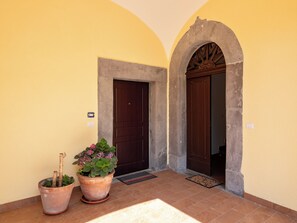 Entrada de un edificio con dos puertas, una planta en maceta y suelo de baldosas.
