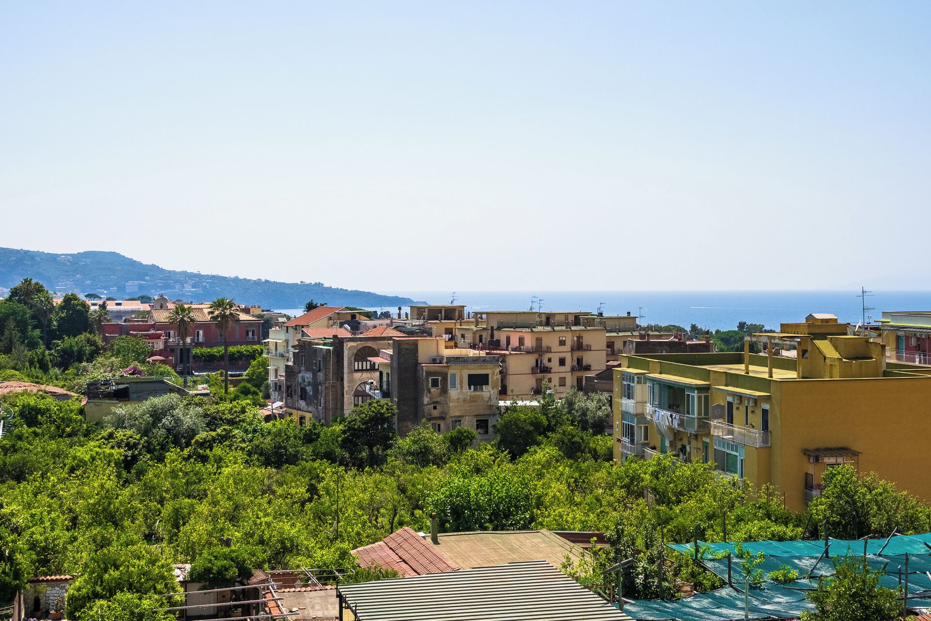 A coastal town with buildings, greenery, and a view of the sea.