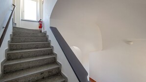 Eine Treppe mit Handlauf, einem Feuerlöscher und einer Tür am oberen Ende.