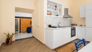 Eine kleine Küche mit weißen Schränken, einem eingebauten Backofen und einer gefliesten Spritzschutzleiste.