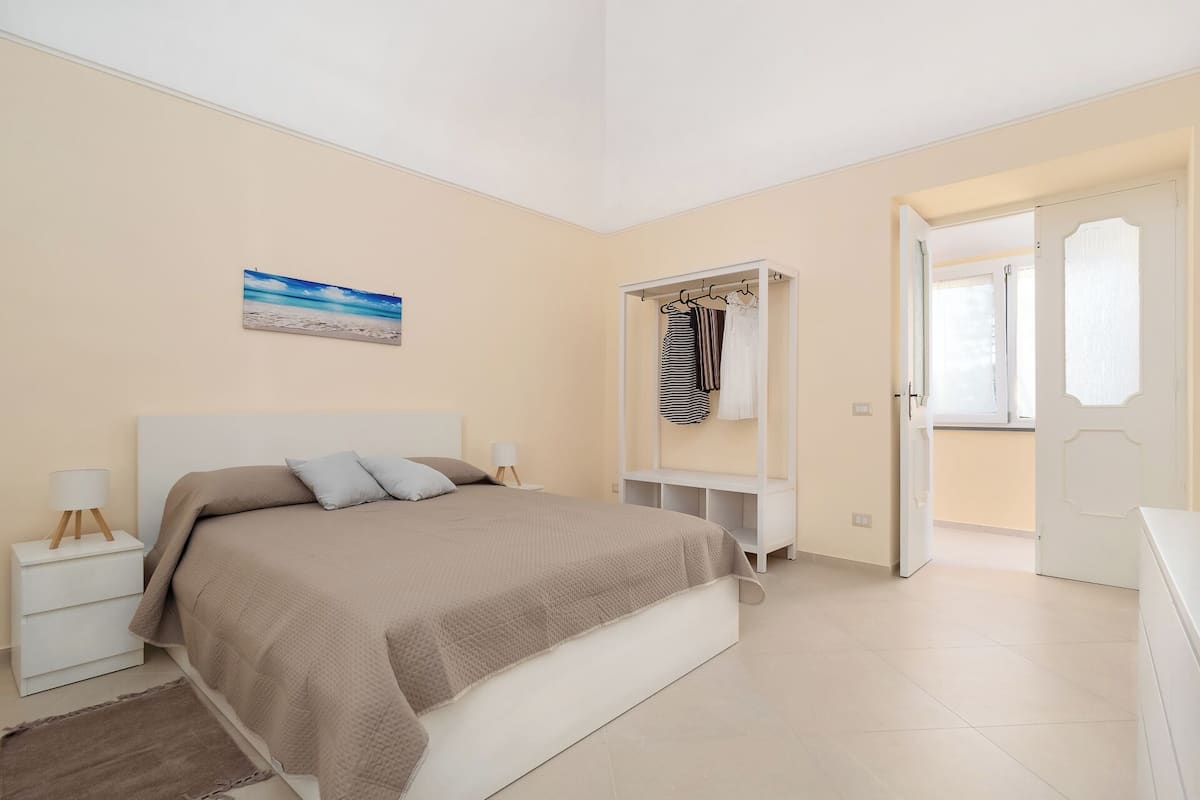 Un dormitorio con cama, mesitas de noche, armario y un cuadro en la pared.