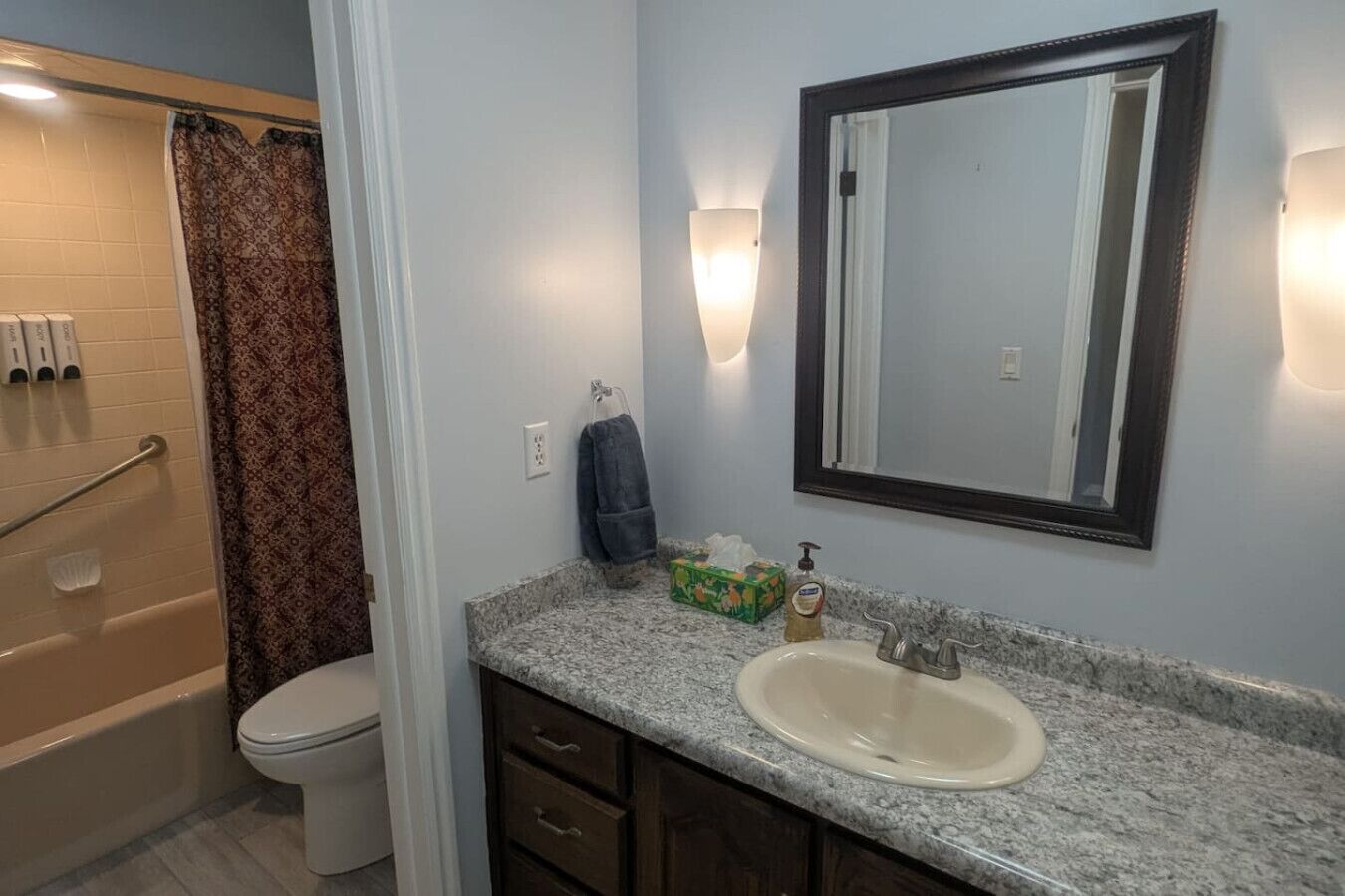 A bathroom with a shower, toilet, sink, and a mirror.