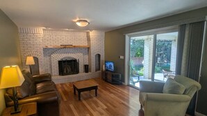 A living room with a brick fireplace, leather sofa, and a television.