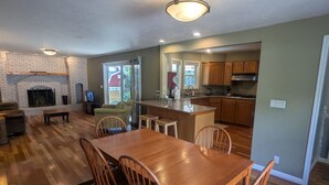 A spacious living room with a fireplace, a dining area with wooden furniture, and a kitchen with wooden cabinets.