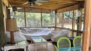 Un espacio al aire libre acogedor con terraza de madera, ventilador de techo y mesa con sillas.