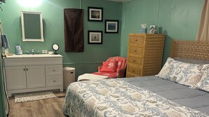 Un dormitorio con una cama, un aparador, una silla y una tocador con espejo.