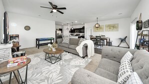 Ein modernes Wohnzimmer mit grauem Sofa, Couchtisch und Deckenventilator.