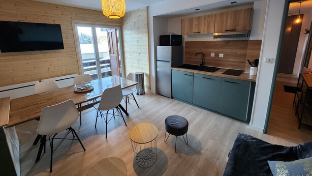 A modern kitchen with wooden cabinets, a stainless steel refrigerator, and a black sink.