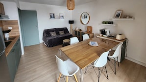 A modern kitchen with a wooden countertop and a dining area with a wooden table and white chairs.