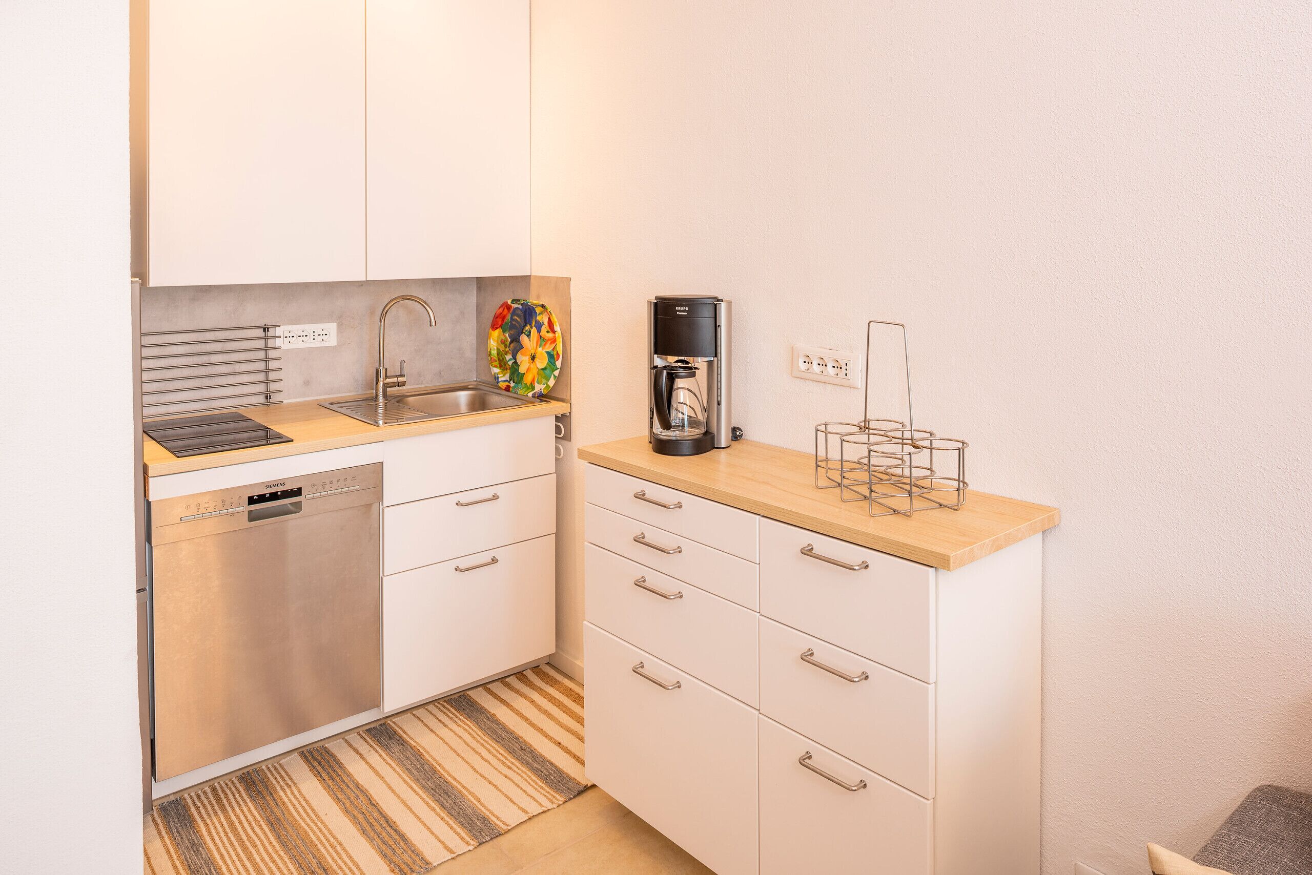 A compact kitchen with a dishwasher, a coffee maker, and a small sink.