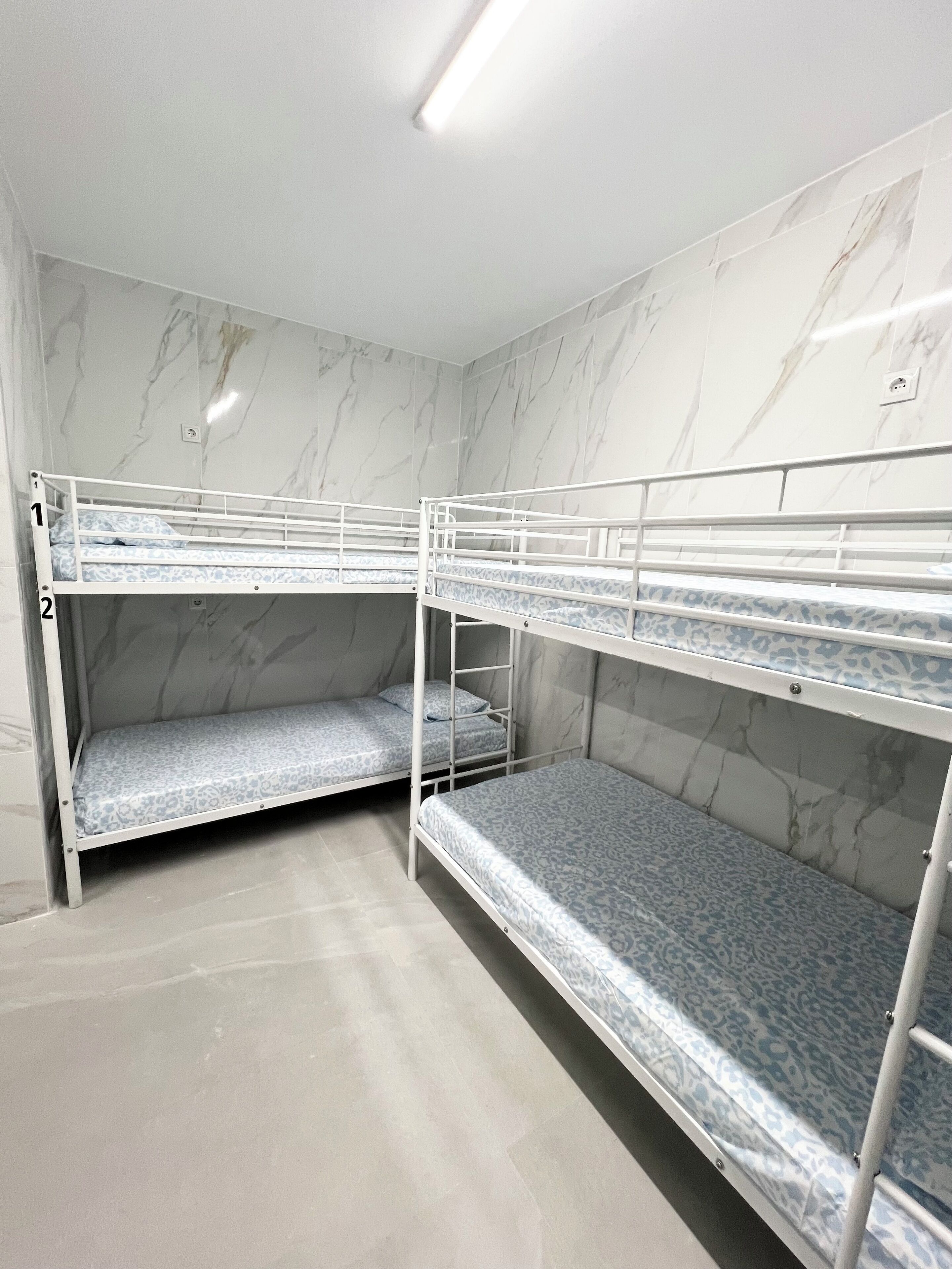A room with three bunk beds, marble walls, and a tiled floor.