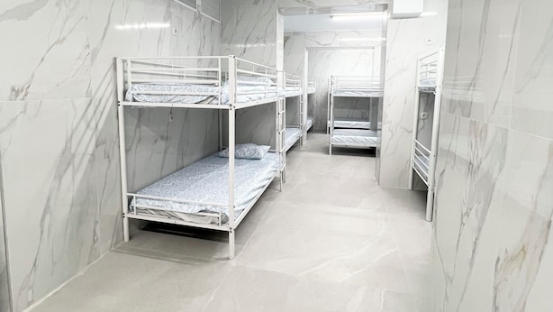 Een kamer met stapelbedden langs de wanden, een betegelde vloer en een marmerachtige wandafwerking.